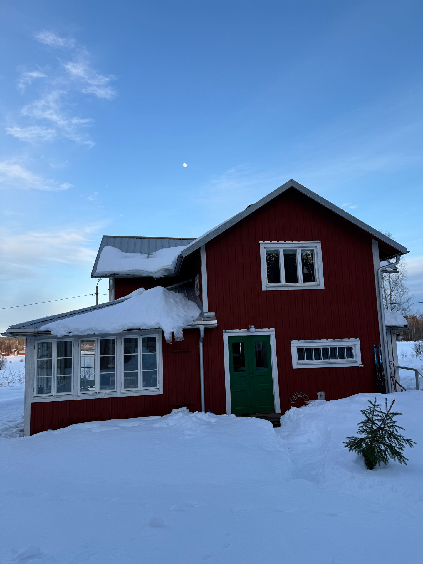 Farfars röda hus med gröna dörrar i vintersnö