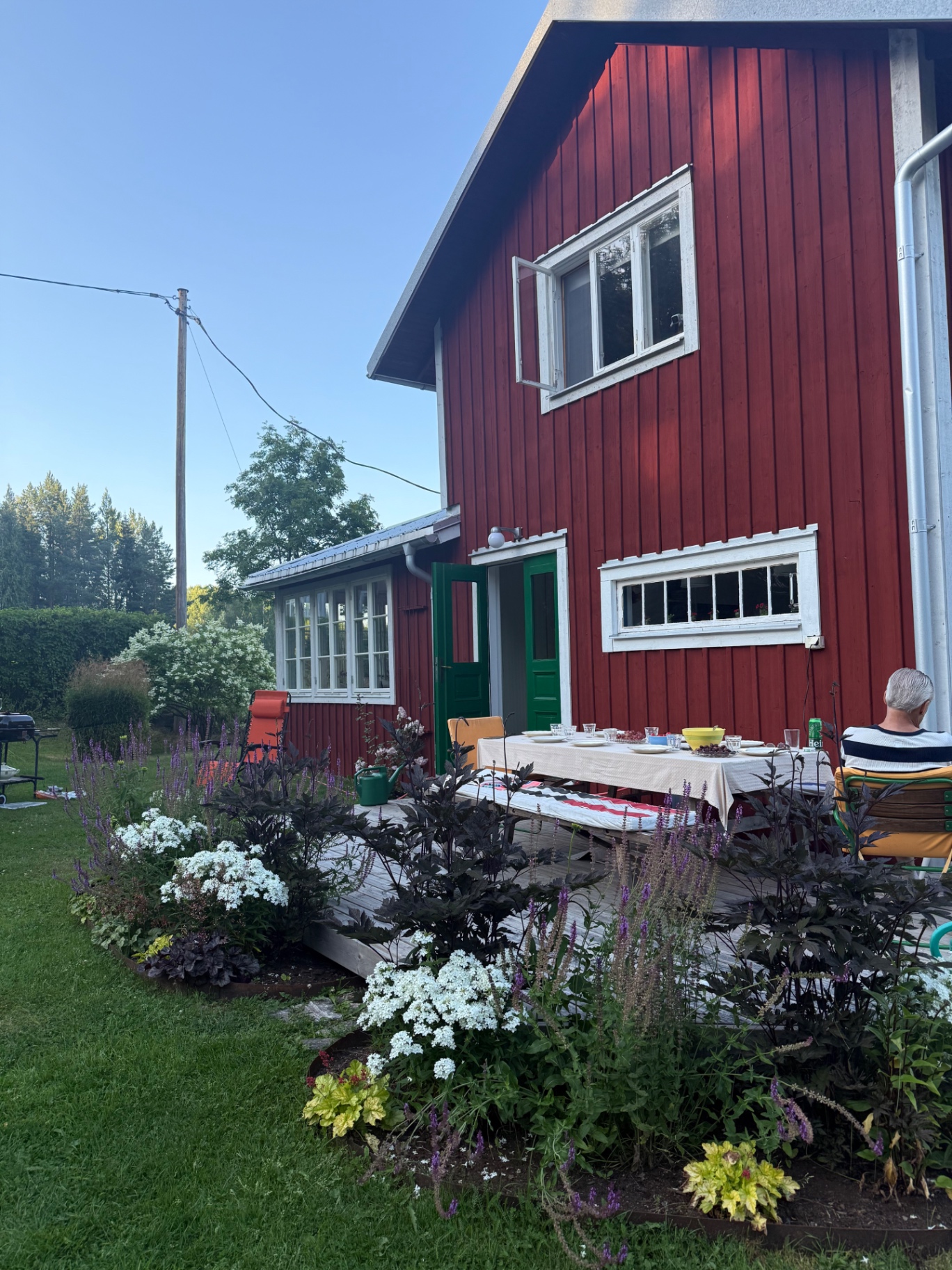 Farfars röda hus och blommande trädgård på sommaren